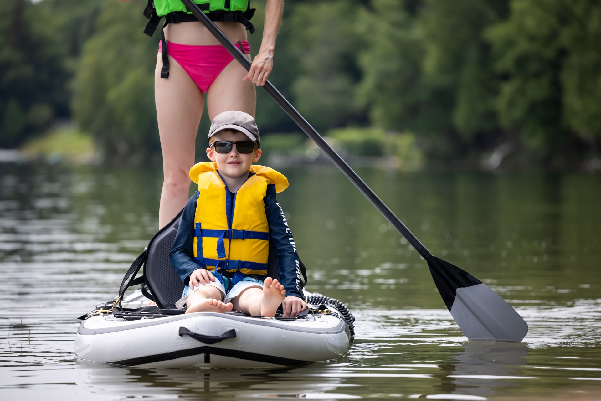 Mother and Son Stand up paddle-boarding on quiet lake during a warm sunny summer vacation day